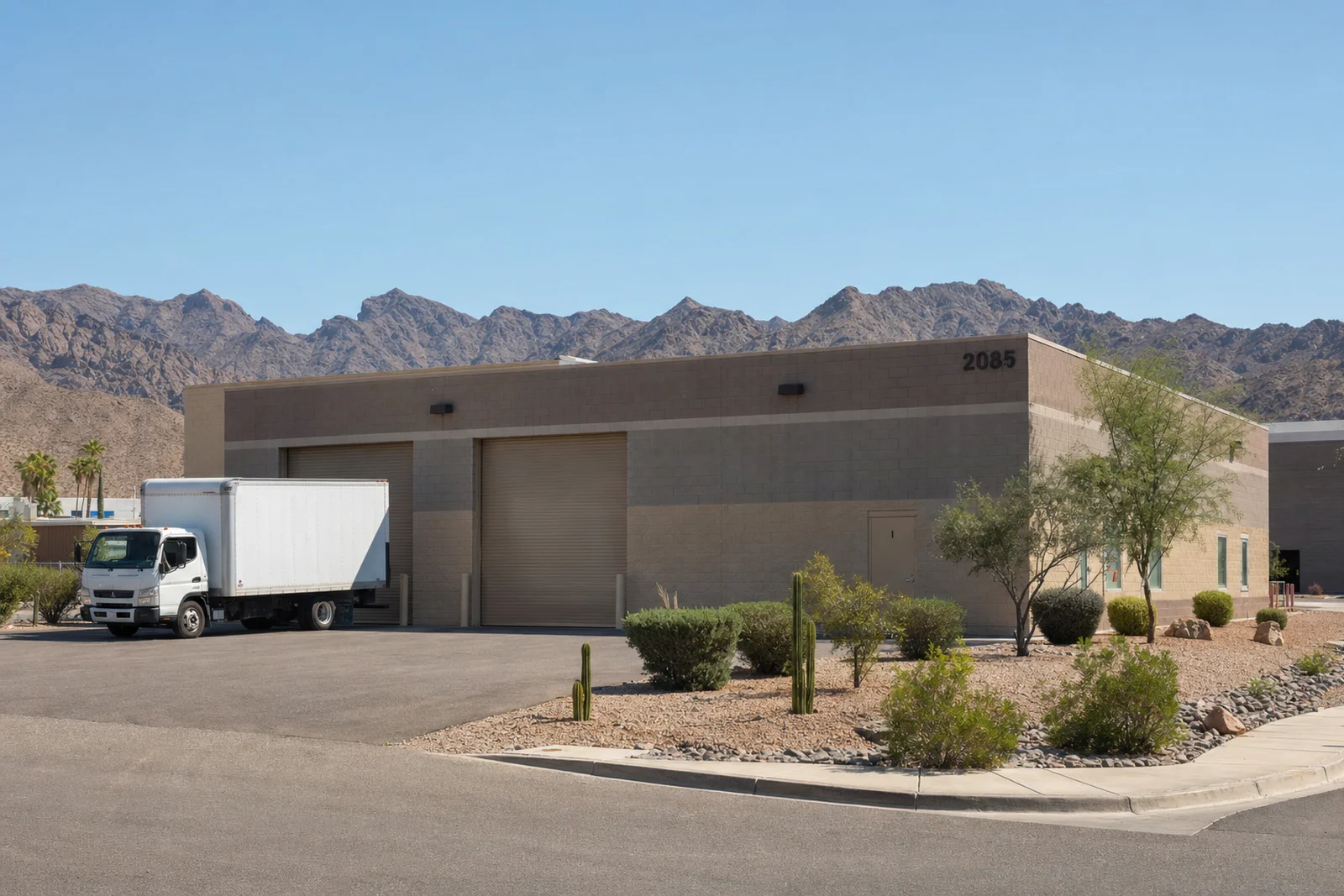 Single-story desert industrial warehouse with a delivery truck at the loading dock, mountains in the background near Lake Havasu City, AZ